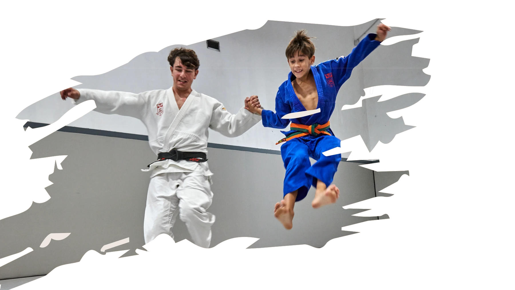 Un entrenador y un niño saltan celebrando en el tatami.