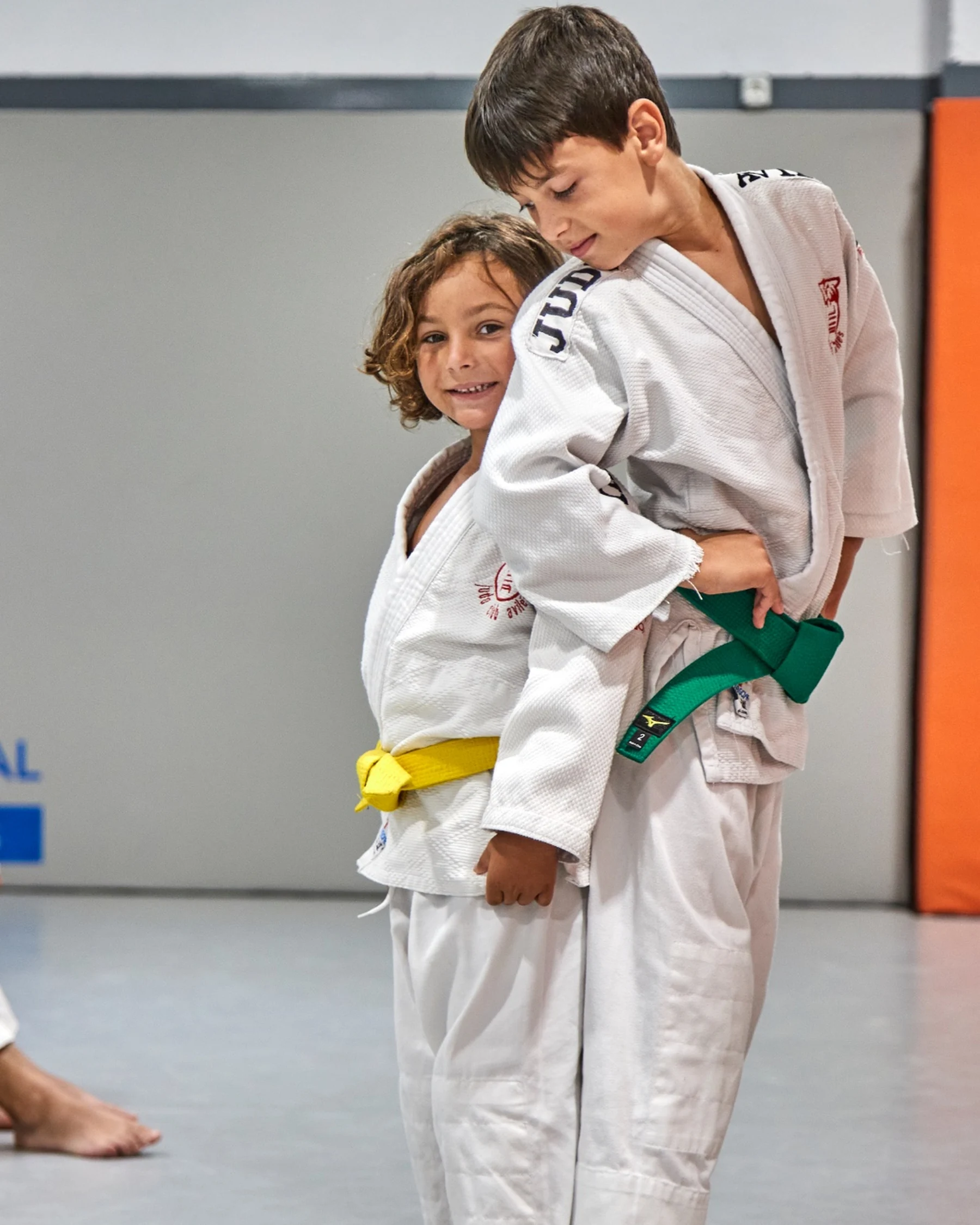 Una niña se apoya sonriendo, algo tímida, en la espalda de un compañero.